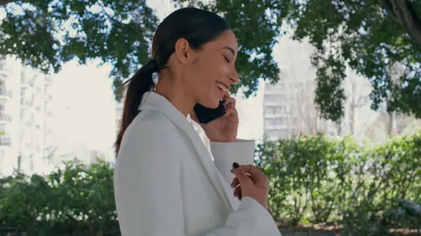 Cep telefonunda gülen mutlu kadın doğada neşeli sohbetlerin keyfini çıkar. Şehir parkında akıllı telefondan konuşan zarif bir iş kadını. Esmer, dedikoducu, cep telefonunu arıyor.