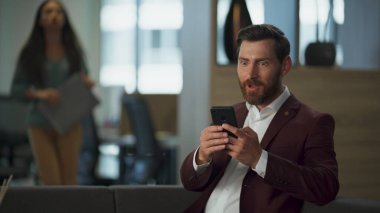 Şok olmuş iş adamı akıllı telefon ekranlı modern finans bürosu iç mimarisi. Mutlu emlakçılar, anlaşma kazanan şirket salonu. Neşeli koç cep telefonu haberlerini okuyor. Pazarlama başarılı çalışma konsepti