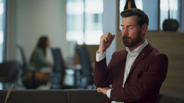 Yorgun iş adamı rahat ofis odasında stres hissediyor. Pazarlama planlarını düşünen ciddi bir beyefendi. Genç girişimci başını sallayarak hareket ediyor. Stresli iş kavramı.