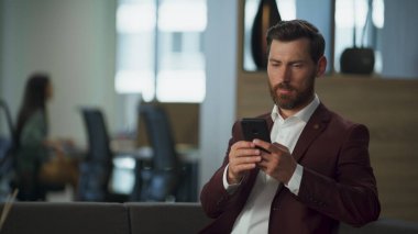 Modern şirket ofisinde cep telefonu ekranı kullanan odaklı emlakçı. Ciddi bir yönetici iş adamı cep telefonu holünün içini arıyor. Elinde akıllı telefon tutan profesyonel bir girişimci. Çalışma konsepti.