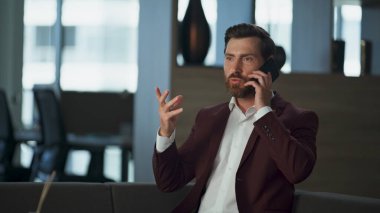 Modern ofiste ciddi bir yönetici cep telefonuyla konuşuyor. Stresli profesyonel iş adamı cep telefonuyla şirket planlarını tartışıyor. Odaklanmış yoğun emlakçı finansal iş kavramı