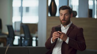 Konforlu salonda şirket anlaşmasını kutlayan sürpriz girişimci. Büyük ofis pencerelerinde modern cep telefonu arayan mutlu bir işadamı. Başarılı finans müdürü çalışma konsepti.