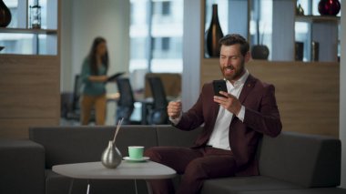 Neşeli iş adamı büyük ofis penceresinin yanında kahve içiyor. Modern konforlu salonda akıllı telefonu elinde tutan başarılı bir finans müdürü. Profesyonel pazarlama girişimcisi sıcak çayla rahatlar.