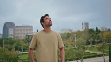 İspanyol adam Green Park 'ta tek başına şehir manzarasını seyrediyor. Sakin çekici turist hafta sonunun tadını çıkarıyor. Rahatlamış traşsız adam şehir yeşilliğinin önünde duruyor tatilde bulutlu bir gün