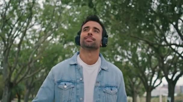 Безтурботний Чоловік Слухає Музику Навушників Йде Красивим Зеленим Парком Сам — стокове відео