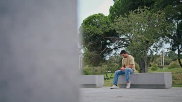 Student Ogląda Zabawny Film Komórce Siedząc Samotnie Ławce Miejskiej Beztroski — Wideo stockowe