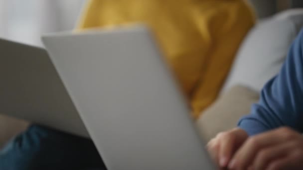 便衣人员双手在键盘上打字 膝上抱着笔记本电脑 一个严肃的女人问她的丈夫在灯塔工作的电脑 两个自由职业者一起完成任务 学生们在舒适的沙发上学习 — 图库视频影像