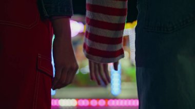 Yakın plan siluet eller neon lambaları tutuyor. Bilinmeyen kadın kolları gece lunaparka dokunuyor. Sevgi dolu sevgililer kaynaşıyor. Aşk ilişkileri kavramı.