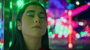 Çekici bir portre, aydınlatılmış bir park. Neon Funfair atlıkarıncasında bekleyen düşünceli gençler. Başarısız bir randevuda hayal kırıklığına uğramış genç bir kadın. Geceleri parti makyajlı rüya gibi güzel bir kadın.