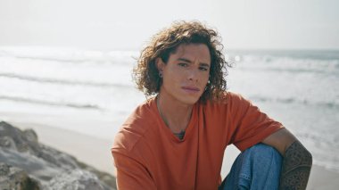 Yazın deniz kıyısında oturan ciddi genç adam hafta sonu kapanıyor. Çekici erkek mankeni plajda kendini yalnız hissediyor. Okyanus kıyısında poz veren kıvırcık stil sahibi, düşünceli yüzlü bir adam..