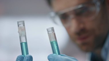 Bioteknoloji uzmanı deney tüplerinin laboratuarda çalışmasıyla sonuçlandı. Gözlüklü gülümseyen bilim adamı aşı araştırmasını tamamladı. Genç biyokimyacı başarılı bir araştırma yapıyor..