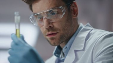 Tıp profesörü, yenilik laboratuarında deneysel madde araştırması yapıyor. Pipet kullanarak test tüpünü dolduran bilim adamı. Gözlük laboratuarı uzmanı yeni aşıyı inceliyor..
