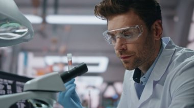 Eczacılık uzmanı ileri düzey laboratuarlardaki numuneleri yakından inceliyor. Laboratuvarda deney tüpü tutan ciddi bir bilim adamı mikroskop arıyor. Bilimsel araştırma yapan odaklanmış teknisyen modern ilaçlar üretiyor.