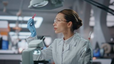 Tıp laboratuarında çalışan mutlu bilim adamı başarılı olduğunu hissediyor. Heyecanlı kadın doktor test tüpünü inceliyor mikroskop arıyor aşı formülü arıyor. Gülümseyen uzman başarılı bir araştırma yapıyor.