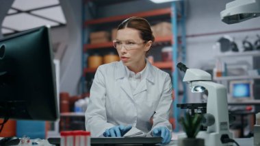 Laboratuarda koruyucu gözlüklerle daktilo yazmakla meşgul bir doktor. Mikroskopta araştırma yapan kadın bilim adamı. Beyaz önlük konusunda uzman kadın örnekleri inceliyor.