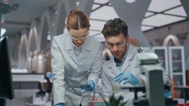 Laboratuvar çalışanları ileri düzey klinikteki bilgisayar verilerine bakarak örnekler üzerinde çalışıyorlar. Deneyimli bilim adamları laboratuvarda araştırma sonuçlarını kontrol ediyorlar. Erkek meslektaşımla birlikte aşıda çalışan kadın kimyager..