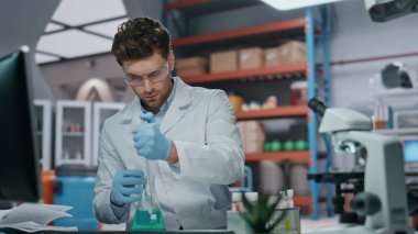 Modern klinikte laboratuvar araştırması yapan bir doktor. Ciddi bir bilim adamı deney tüpünü yenilikçi ilaçlarla dolduruyor. Gözlüklü, ilaçlarla deney yapan zeki bir araştırmacı..