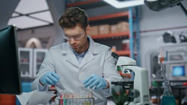 Tıbbi teknisyen, hastalığın yakın çekiminden elde edilen yeni aşıyı araştırıyor. Deney tüpü tutan odaklanmış bilim adamı mikroskoba bakıyor. Bilgisayar ekranındaki verileri kontrol eden genç bir araştırmacı