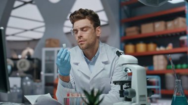 Düşünceli bilim adamı yenilik laboratuarında yeni aşı analizi yapıyor. Mikroskop üzerinde çalışan ciddi bir mikrobiyoloji uzmanı. Deneysel ilaçlarla test tüpü tutan genetik uzman..