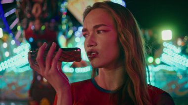 Lunaparkta hoparlörden konuşan sinirli kız. Mutlu olmayan genç kız festival haftasonunda sesli mesaj kaydediyor. Güzel genç bayan neon atlıkarınca karnavalında bekliyor..