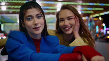 Yakından gülümseyen kızlar lunapark atlıkarıncasında poz veriyorlar. Çarpışan arabaya binen mutlu arkadaşlar aydınlanmış lunaparkın tadını çıkarıyorlar. Göz kamaştırıcı sevgili çift kameraya sarılıyor. Arkadaşlık bağı anları