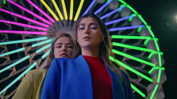 Moda modelleri neon ışıklı dönme dolaba bakıyor. Lunaparkta poz veren iki kız. Göz kamaştırıcı rahibeler yanıp sönen ışıklarda eğleniyor. Modayı takip eden sokak arkadaşları.