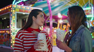 En iyi arkadaşlar Luna Park 'ta dedikodu yapıyorlar. Atıştırmalık yiyen gülümseyen gençler yaz festivali hakkında bilgi paylaşıyorlar. Neşeli kızlar neon ışıklı atlıkarıncada hafta sonunun tadını çıkarır.