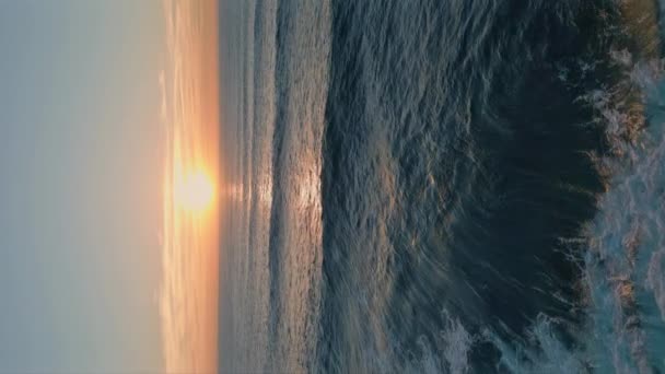 深い青い海の水の空中ビューに輝くイディラックな海の日没 超遅い動きで海岸に転がっている絵の波 海面を垂直方向にリッピングしたゴールデンサンライト — ストック動画