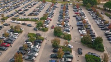 Şehir parkında yaz günü parka park edilmiş birçok araba var. Yayalar kaldırımda yürürken, otomobiller geniş otoparkta boş yerlere bakıyorlar. Çeşitli araçlar için kentsel alan
