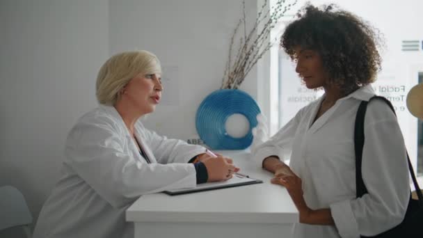 Lächelnde Krankenschwester Spricht Klient Der Rezeption Nahaufnahme Afroamerikaner Besuchen Schönheitssalons — Stockvideo