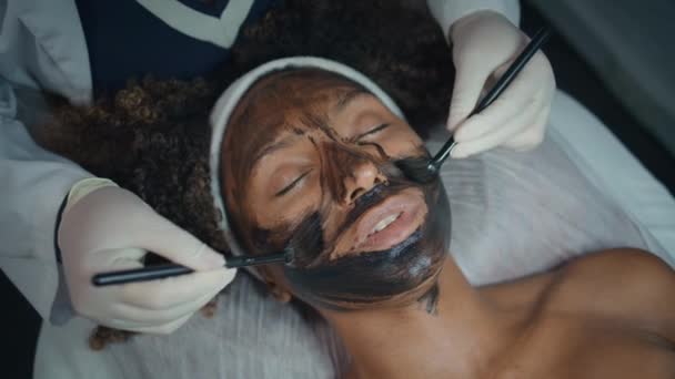 Nahaufnahme Kosmetikerin Pinselmaske Für Peeling Salon Schöne Modell Draufsicht Afrikanisch — Stockvideo