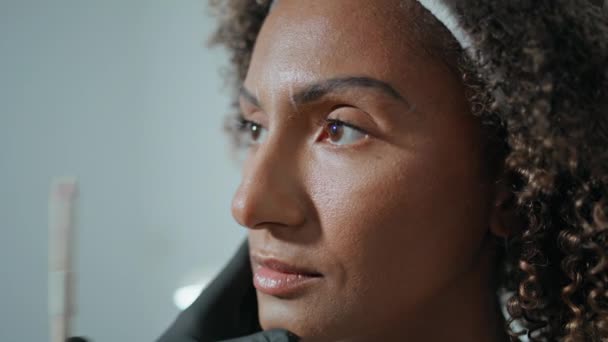 クリニックのボトックス注射部位を示す閉鎖化粧品学者 アフリカ系アメリカ人女性が美容院を訪れ 顔の手術に備えています 未知の医者は審美的な処置の前に顔の形を検査します — ストック動画