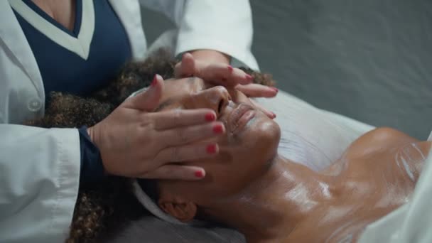 Cosmetologist Mãos Esfregando Creme Cara Hidratar Procedimento Spa Closeup Afro — Vídeo de Stock