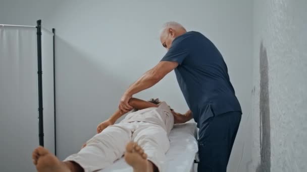 Masér Dělá Fyzioterapii Klinice Manipulace Prevencí Traumatu Šedé Vlasy Fyzioterapeut — Stock video