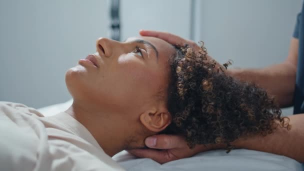 躺在理疗沙发上的妇女特写 临床病人在康复过程中睁开眼睛 缓解疼痛 按摩时 不明身份的脊椎按摩师的手触摸着按压的头 保健系统概念 — 图库视频影像