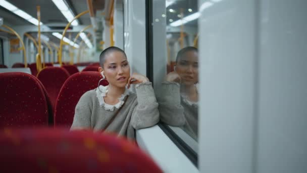 快適な座席現代列車に座っているワイヤレスイヤホンで音楽を聴く少女の乗客 笑顔の短い髪の女性は 鉄道輸送で通勤ヘッドフォンで好きな曲を楽しんでいます 観光コンセプト — ストック動画