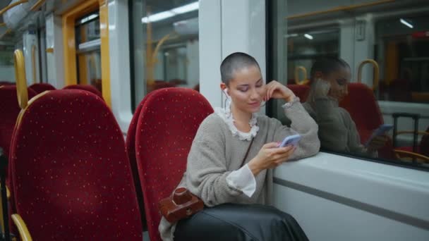 現代電車でスマートフォンソーシャルメディアを閲覧する幸せな女性 スマイルショートヘアガールは 速い輸送に座っている携帯電話のスクリーンを見ています 鉄道リスニングミュージックで旅する魅力的な非公式の女性 — ストック動画