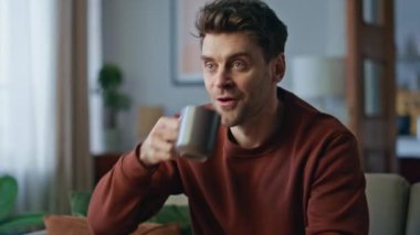 Rahat adam rahat koltukta oturup kahve içiyor. Oturma odasında televizyon seyreden çekici sakin bir adamın portresi. Kanepede TV şovuna katılan yakışıklı erkek hippi..