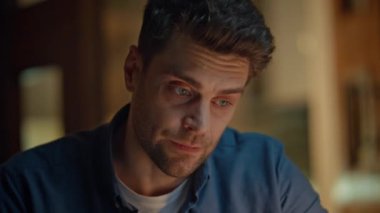 Evde geç saatlere kadar çalışmaktan endişelenen serbest çalışan biri. Sinirli somurtkan adam akşam apartmanında video görüşmesi yapıyor. Esmer adam lamba ışığında iş anlarını çözerken arka planı bulanıklaştırıyor.