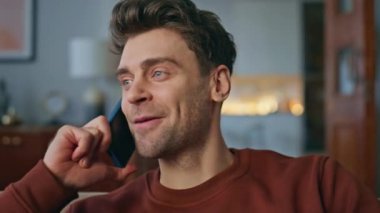 Hafta sonu evde gülümseyen bir hipster 'ın cep telefonunu aramasının portresi. Neşeli yakışıklı adam dairede hoş telefon konuşmalarının tadını çıkarıyor. Mutlu rahat adam akıllı telefondan buluşma ayarlıyor. Yakın plan..