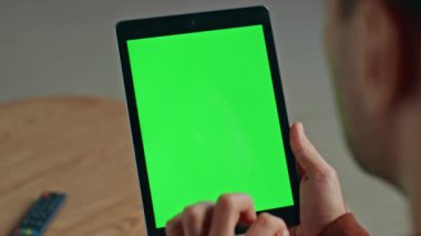 Adamın elleri tablet dokunmatik ekranı araklıyor. Ev işyerinde yakın plan çekimde. İş için elinde yeşil ekran ekran bilgisayarı tutan tanınmamış bir serbest yazar. Modern ofiste kromakey aygıtı kullanan yönetici 