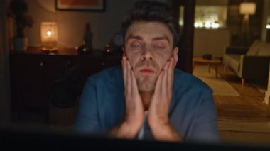 Çok çalışan işkolik gece yakın plan çekimde bilgisayar ekranına konsantre olmaya çalışıyor. Yorgun bir iş adamı bilgisayar başında akşam dairesinde çalışıyor. Yorgun adam elleriyle yüzüne dokunuyor.