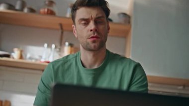Ciddi bir adam, mutfaktaki bilgisayarla yakından ilgilenir. Tıraşsız adam hafif evde bilgisayar ekranının klavye yazmasını izliyor. Kaşlarını çatan serbest çalışan kahvaltıda e-posta atarak soruları cevaplıyor