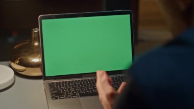 Video konferansı için yeşil ekran dizüstü bilgisayar kullanan tanınmayan serbest çalışan gece ofisi kapanışı. Tanımlanamayan genç adam web kamerasında tek başına konuşuyor. Krom tuş ekranıyla çalışan adam