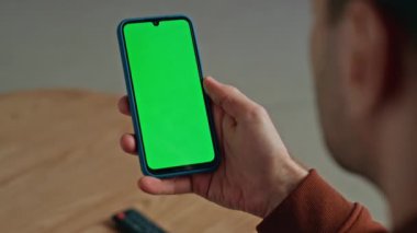 Krom anahtarlı cep telefonu kullanan tanınmayan bir adam apartman dairesine yakın oturuyor. Evde elinde yeşil ekran akıllı telefon mesajı tutan bir adam. Erkek, serbest çalışan, kapalı alandaki model cep telefonunda gezinen bir uygulama