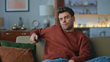 Sıkıcı hippi rahat koltukta yalnız başına film izlemeyi tercih ediyor. Hoşnutsuz adam televizyon kanallarını değiştiriyor uzaktan kumandaya basıyor. Yorgun adam evde oturan tatminsiz televizyon programı.