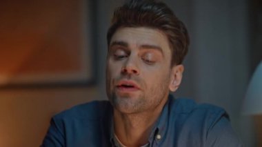 Ciddi bir iş adamı yüzü akşam evde ağ hakkında konuşuyor. Traşsız, odaklanmış bir adam cep telefonu projesine parmak basıyor ve gece yarısı iç mekanda çalışıyor. Akıllı telefonu tutan el kol hareketi yapan adam.