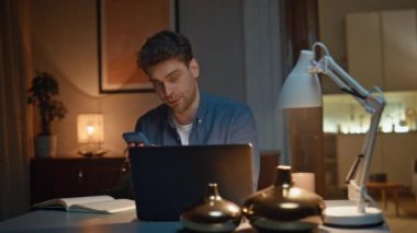 Akşamları evde bilgisayarla sanal konferans görüşmesi yapmakla meşgul. Elinde cep telefonu olan ciddi traşsız bir adam kağıda not alıyor. Bilgisayar iletişiminde çalışan kendine güvenen bir adam.