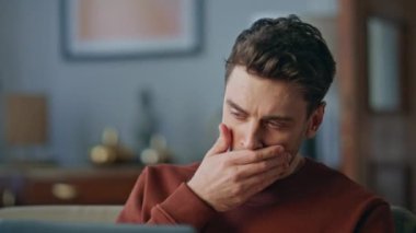 Aşırı çalışan serbest çalışan, evde dizüstü bilgisayar görüntüsü olan bir portre. Bunalmış genç uzaktan kumandalı yönetici bilgisayarda çalışmaktan yorgun düşüyor. Yorgun adam apartmandaki iş sorunlarını çözüyor..