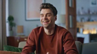 Mutlu adam televizyon programının keyfini çıkarıyor. Rahat ev kanepesinde dinleniyor. Yakın çekim. Yakışıklı adam tek başına favori televizyon kanalı gibi gülümsüyor. Tasasız hippi kahve içiyor. Oturma odasındaki kanepede tek başına film izliyor..